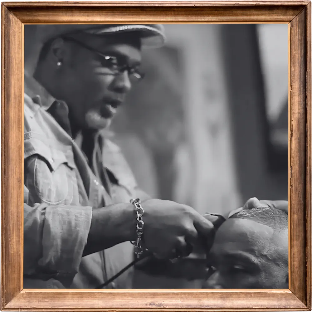 Black-and-white photo in a wooden frame of Doc cutting a client’s hair